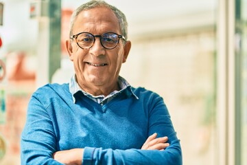 Wall Mural - senior grey-haired man with arms crossed smiling happy standing at the city.
