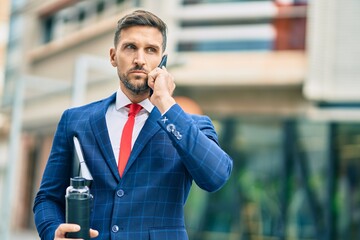 Poster - Young caucasian businessman with serious expression talking on the smartphone at the city.