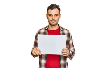 Canvas Print - Young hispanic man holding blank empty banner thinking attitude and sober expression looking self confident