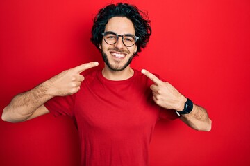 Poster - Handsome hispanic man wearing casual t shirt and glasses smiling cheerful showing and pointing with fingers teeth and mouth. dental health concept.