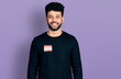 © Krakenimages.com - Young arab man with beard wearing hello my name is sticker identification looking positive and happy standing and smiling with a confident smile showing teeth