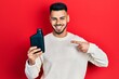 © Krakenimages.com - Young hispanic man with beard holding motor oil bottle smiling happy pointing with hand and finger