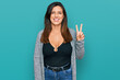 © Krakenimages.com - Beautiful hispanic woman wearing casual clothes showing and pointing up with fingers number two while smiling confident and happy.