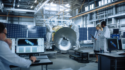 Team of Engineers Working on Satellite Construction, Use Tablet Computer Talk about Data. Aerospace Spaceship Manufacturing Facility: Team of Scientists Building Spacecraft for Space Exploration 