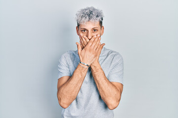 Young hispanic man with modern dyed hair wearing casual grey t shirt shocked covering mouth with hands for mistake. secret concept.