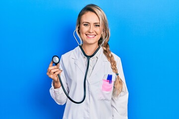 Sticker - Beautiful young blonde doctor woman holding stethoscope with a happy and cool smile on face. lucky person.