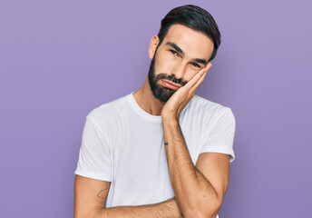 Young hispanic man wearing casual white t shirt thinking looking tired and bored with depression problems with crossed arms.