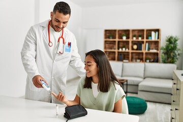 Doctor measuring glucose to latin woman at clinic