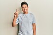 © Krakenimages.com - Teenager hispanic boy wearing casual grey t shirt showing and pointing up with fingers number two while smiling confident and happy.