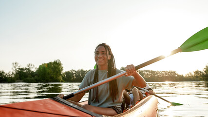 Active young woman smiling, enjoying a day kayaking together with her boyfriend in a lake on a late summer afternoon