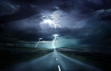 extreme weather conditions. an empty landscape with a road leading into a powerful thunderstorm with