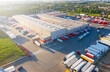 © Golden eagle - Logistics park with warehouse and outside storage of wooden pallets. Semi-trailers trucks standing on car parking and waiting for loading and unloading goods at ramps. Aerial view