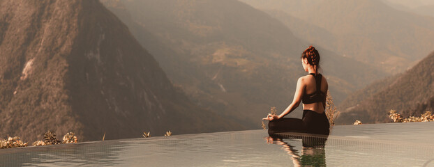 Banner Calm of Athletic Asian woman practice yoga Lotus pose on the pool in the morning in front of beautiful nature views,Healthy woman breathing and meditation yoga comfortable and relax,Warm tone