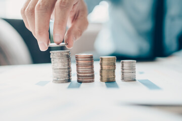 Hand putting money coins stack growing, saving money for finance accounting concept.