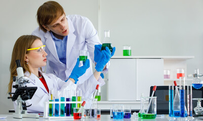 Sticker - Caucasian man and woman scientist are discussing about testing results. Man hold test tube and science equipment microscope, many test tube put on table in laboratory