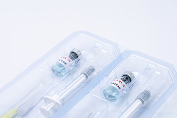 Covid-19, flu, coronavirus liquid vaccine vial bottle and syringe set in plastic package container preparing for injection on white background. Vaccination for fight Covid-19 virus concept.