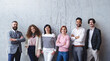 © Halfpoint - Portrait of group of entrepreneurs standing against concrete wall indoors in office, looking at camera.