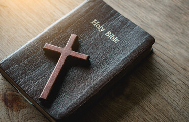 the cross over the bible on wood table with window light.christian backgound