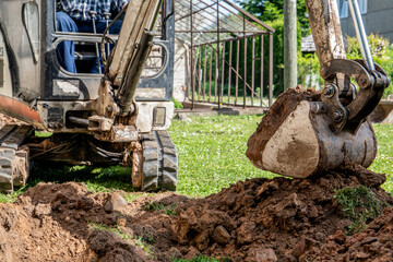 Mini excavator with excavated pile of earth. Garden improvement and landscaping