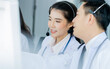 © Ann Rodchua - Selective candid Focus Asian beautiful female doctor smiling with headsets, sitting, monitoring and working with colleagues in hospital to advise online telemedicine to patients with service mind.