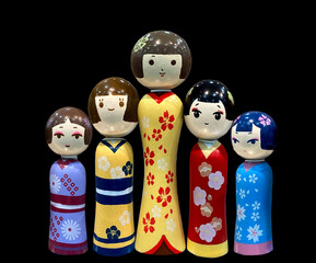 colorful Japanese wooden dolls isolated against black background