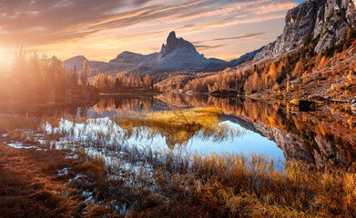 Fototapete - Magic sunny morning scene in autumn forest. Splendid Alpine lake in mountain valley with majestic rocky mount on background. Amazing nature landscape. Wonderful natural background. Vivid wallpaper