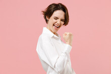 Young Fun Overjoyed Successful Employee Business Woman Corporate Lawyer In Classic Formal White Shirt Work In Office Do Winner Gesture Clench Fist Say Yes Isolated On Pastel Pink Background Studio.