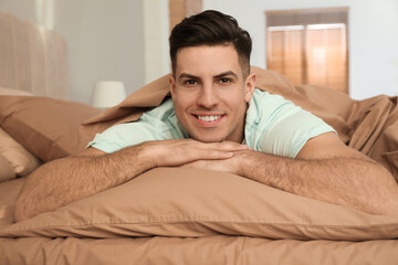 Wall Mural - Man lying in bed with brown linens at home