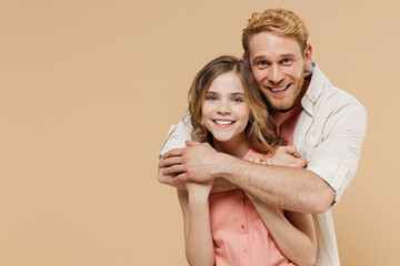 Wall Mural - Young smiling happy parent man have fun with child teen girl in casual pastel clothes. Daddy little kid daughter hugging stand behind isolated on beige background. Father's Day Love family concept