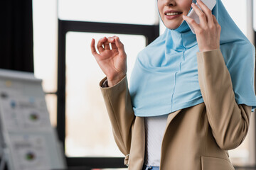 Wall Mural - cropped view of muslim businesswoman gesturing while talking on smartphone