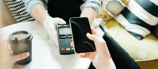 Mobile and safety wireless payment using cell phone and bank terminal. Coffee small business, close-up