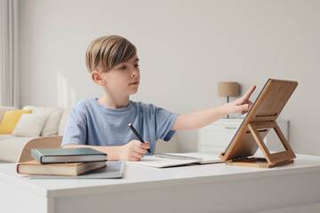 Wall Mural - Boy doing homework with tablet at table indoors