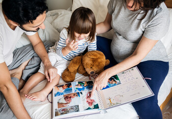 Wall Mural - Pregnant family looking through a family photo album