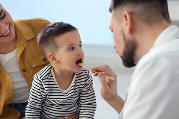 Wall Mural - Mother and son visiting pediatrician in hospital. Doctor examining little boy