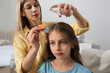 © New Africa - Mother using nit comb and spray on daughter's hair at home. Anti lice treatment
