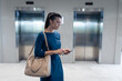 © Wavebreak Media - Caucasian businesswoman using smartphone while waiting for the lift at modern office