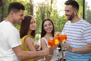 Wall Mural - Friends clinking glasses of Aperol spritz cocktails at outdoor cafe