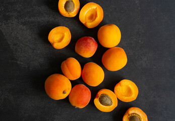 Ripe apricots on the dark smooth background. Close up shot with top view and copy space. Advertising banner with contrast orange summer fruits.  