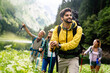 © NDABCREATIVITY - Group of smiling friends hiking with backpacks outdoors. Travel, tourism, hike and people concept.