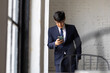 © NVB Stocker - Asian Business man in suit and eyeglasses using mobile smart phone in the office