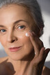 © Yakobchuk Olena - Senior lady receiving moisturizer cream treatment at her skin under the eye