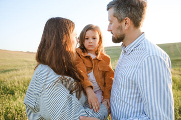 Wall Mural - A hipster family walks in a summer field.