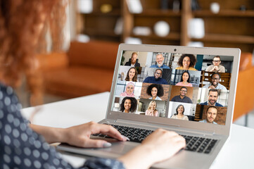 Wall Mural - Red-haired curly woman sitting at the laptop, chatting with friends or colleagues via video meeting, discussing the new project, teaching online,making video call to group of diverse people