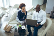 © Wavebreak Media - Two diverse male and female business colleagues sitting and using laptop