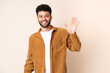 © luismolinero - Young Moroccan man isolated on beige background saluting with hand with happy expression