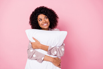 Wall Mural - Photo of shiny sweet curly dark skin woman dotted nightwear holding white pillow looking empty space isolated pink color background