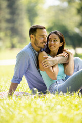 Wall Mural - Affectionate young couple sitting on the green grass