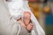 The sacrament of the baptism of a child in an Orthodox church, the baby's feet in a white veil close-up.

