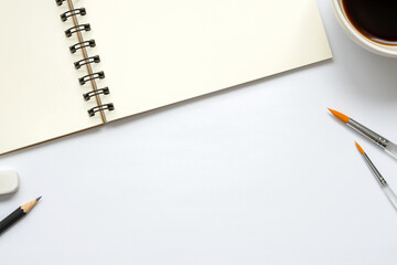 Wall Mural - open blank notebook with a cup of coffee, paintbrush, pencil and eraser on white background, copy sp