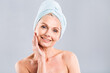 © denis_vermenko - Portrait of smiling senior woman feeling soft skin with hand after spa bath. Mature woman draped in towel looking at camera. Lady in bathrobe after shower isolated over white background.